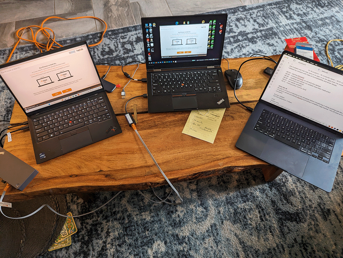 Three laptops on a living-room coffee table transferring everything to a new computer