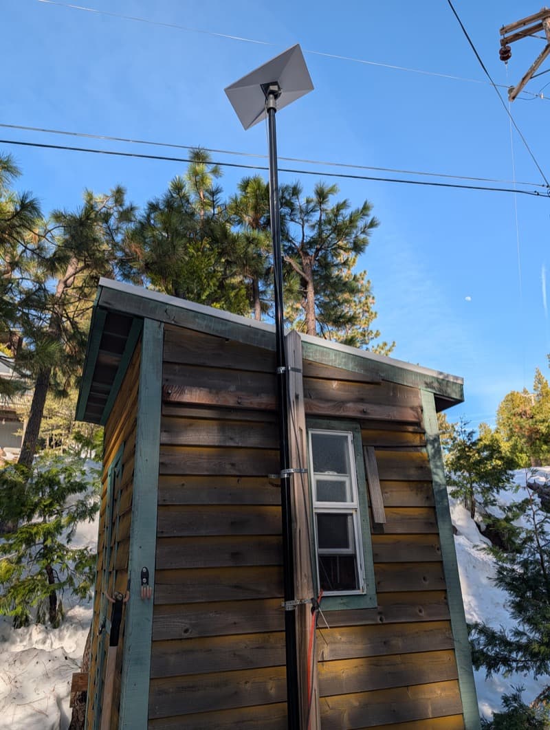 Starlink dish mounted on a pole above a cabin roof after installation