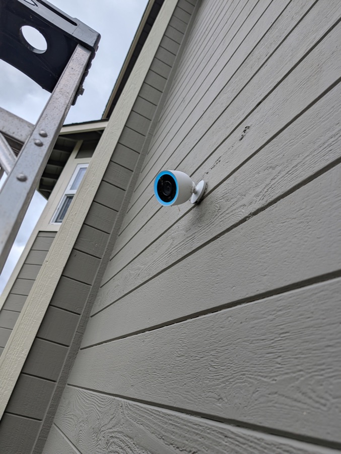A Google Nest outdoor camera mounted on the side of a house, ladder still up from the install