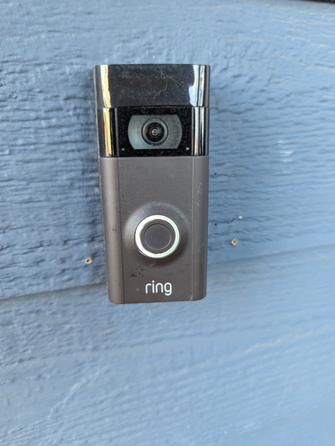 A Ring video doorbell mounted on blue wood siding